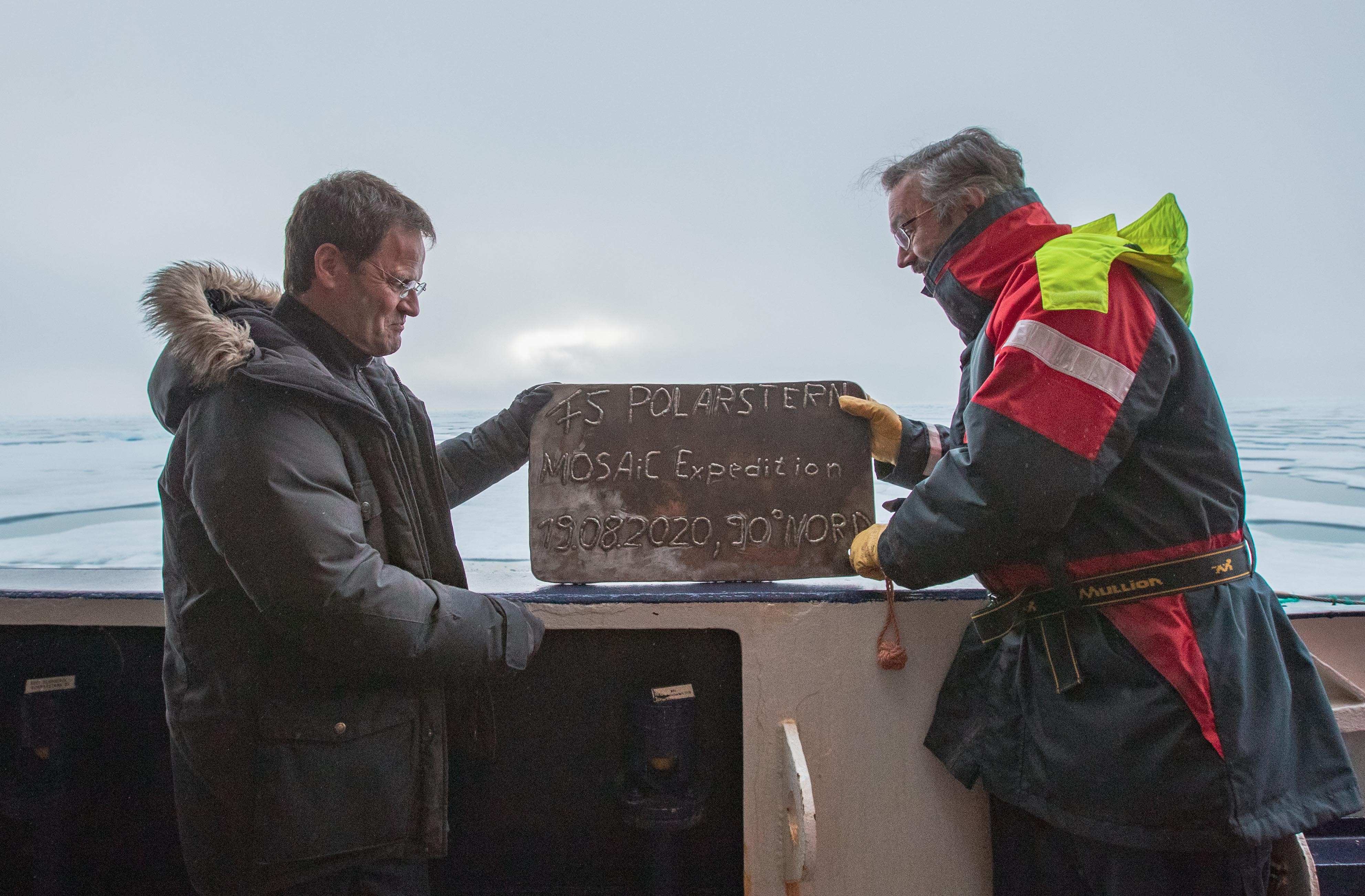 The MOSAiC chief scientist and Polarstern captain hold a commemorative plaque for the North Pole visit