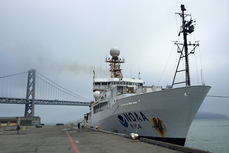 On a foggy day, the NOAA research vessel Ronald H. Brown is shown docked in front of the San Francisco-Oakland Bay Bridge.
