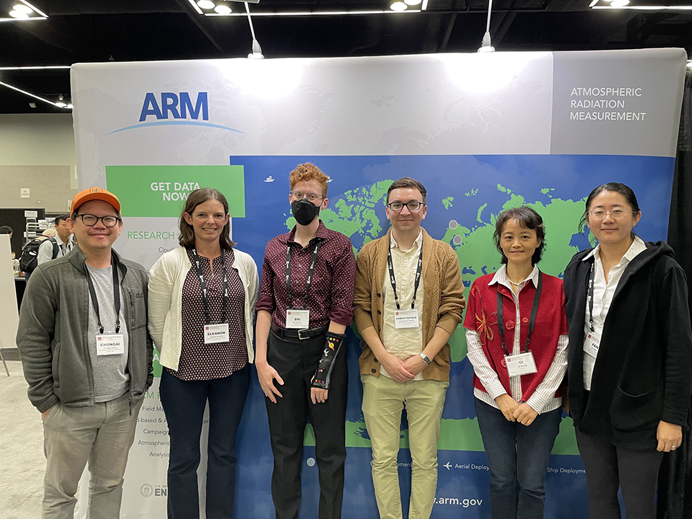 From left to right, Chongai Kuang, Eleanor Browne, Bri Dobson, Christopher Niedek, Qi Zhang, and Fan Mei stand together in front of a large world map with dots indicating where ARM has held field campaigns.