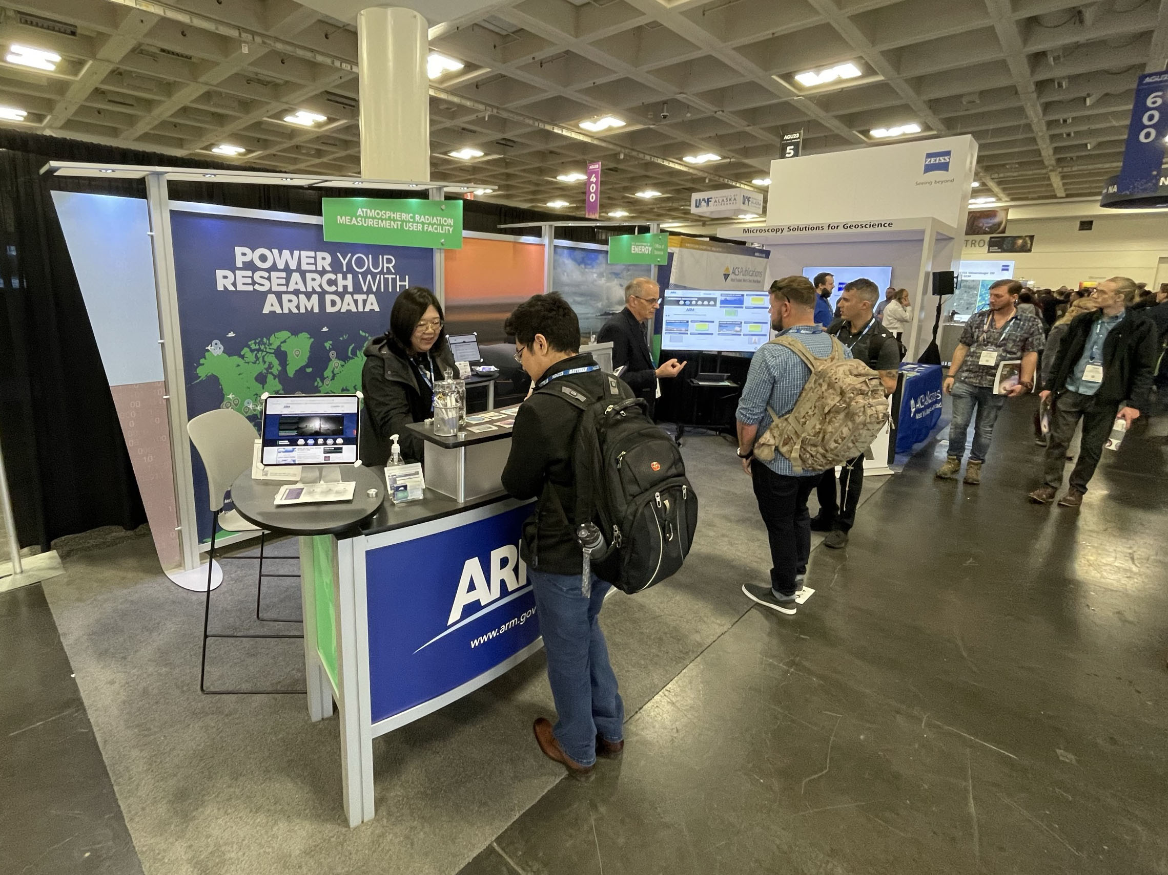 Visitors come to get information at the ARM booth, which includes text saying, "Power your research with ARM data."