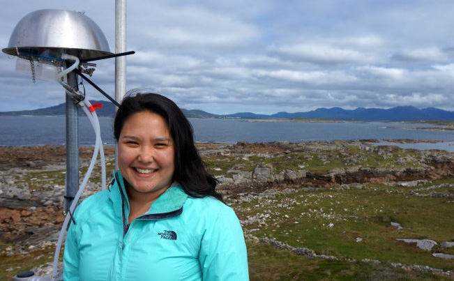 Christina McCluskey, wearing an aqua-colored North Face jacket, poses on rocky shoreline on a cloudy day in western Ireland.