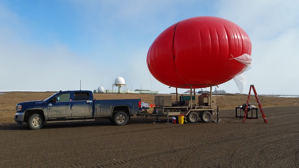 A red tethered balloon rests on a trailer attached to a pickup truck at the Oliktok Point, Alaska, site.
