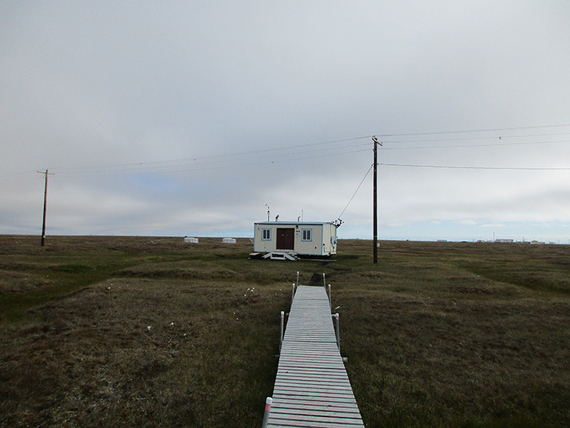 A trailer on tundra underneath a cloudy sky