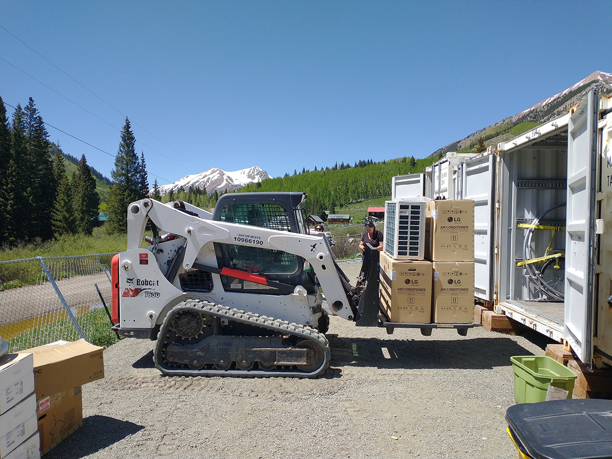 Three boxes with LG Air Conditioner on their sides are stacked on top of a Bobcat platform.