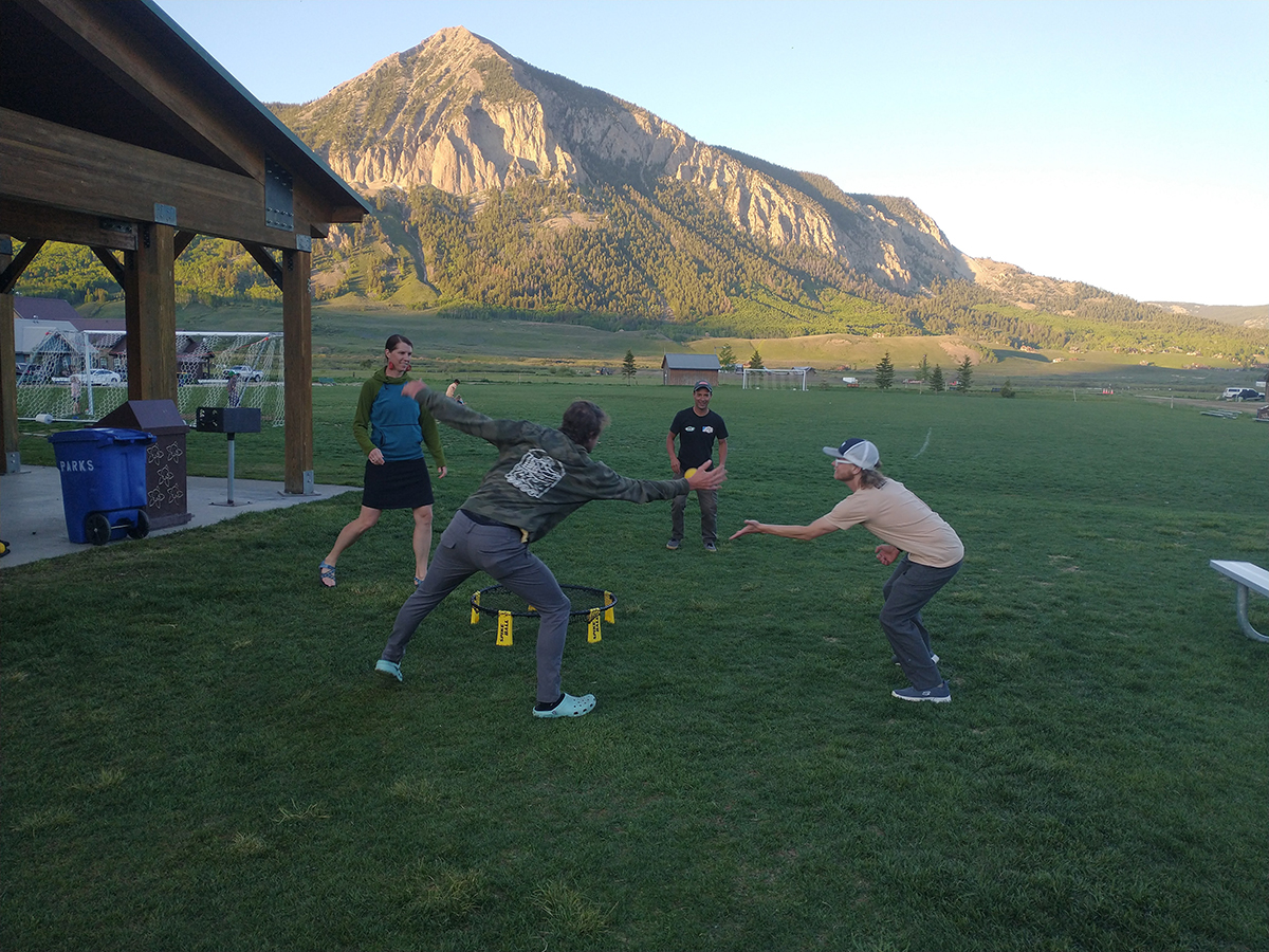 In an open park field, two people are leaning over for a ball coming their way.