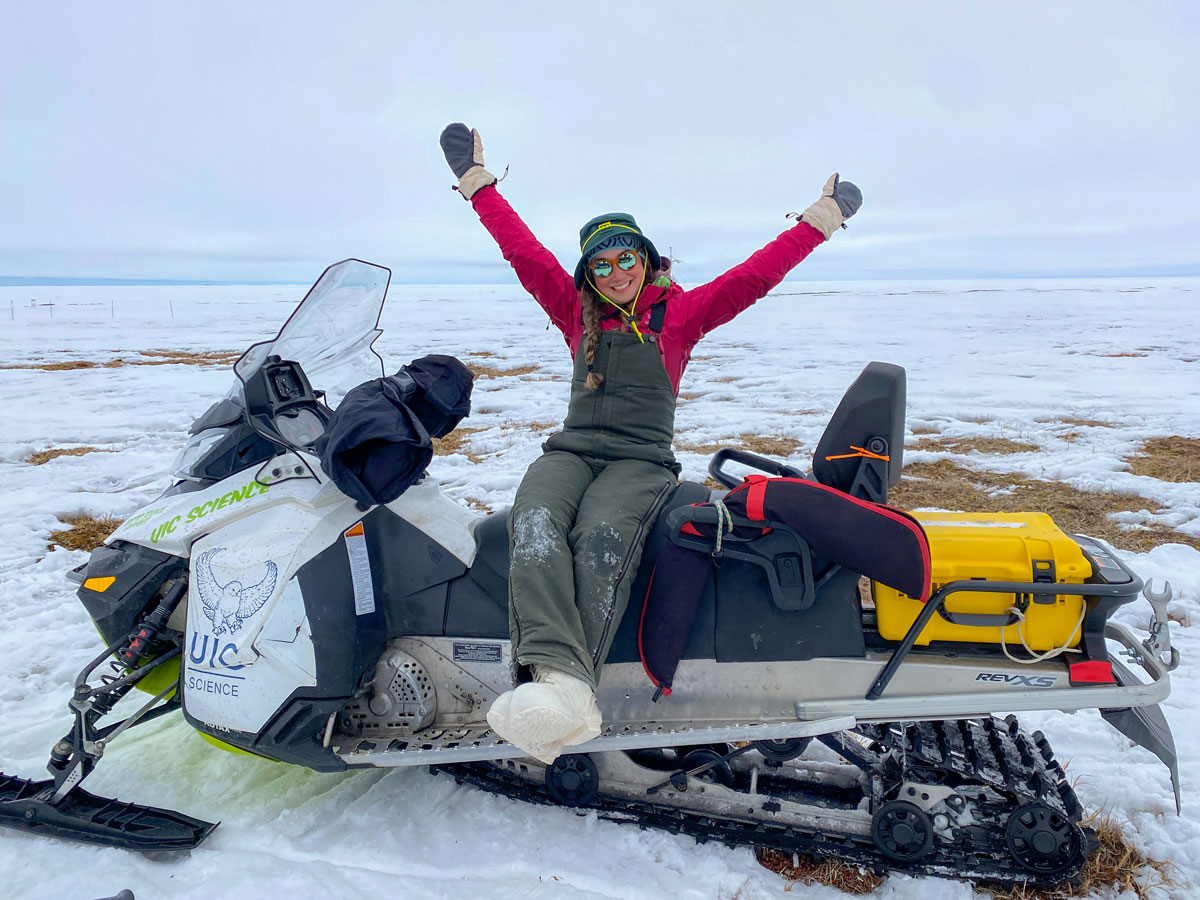 Wearing winter clothes in mid-June, Serina Wesen raises her hands and smiles for a picture in Utqiaġvik, Alaska.
