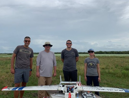 Gijs de Boer, Michael Jensen, Michael Rhodes, and Radiance Calmer stand with a RAAVEN uncrewed aircraft.