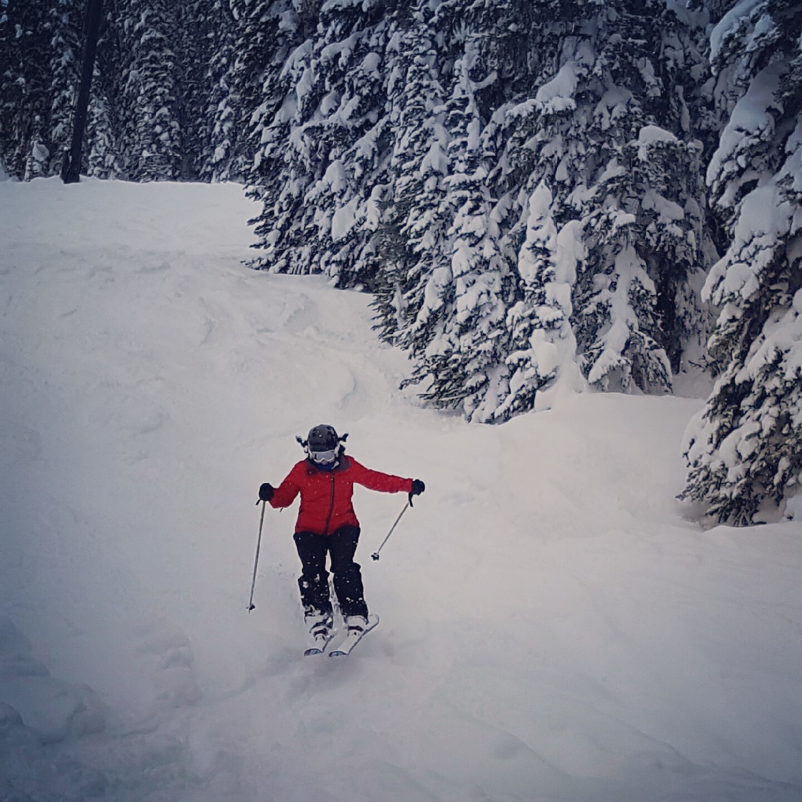 Christina McCluskey wears a red jacket and black snow pants as she navigates a ski course.