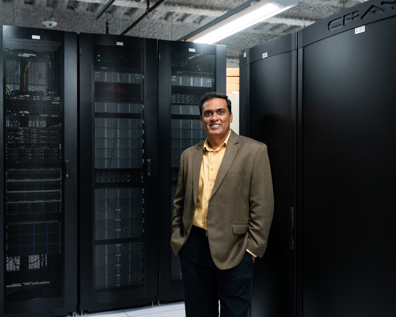 Giri Prakash smiles in front of the Cumulus high-performance computing cluster, left.