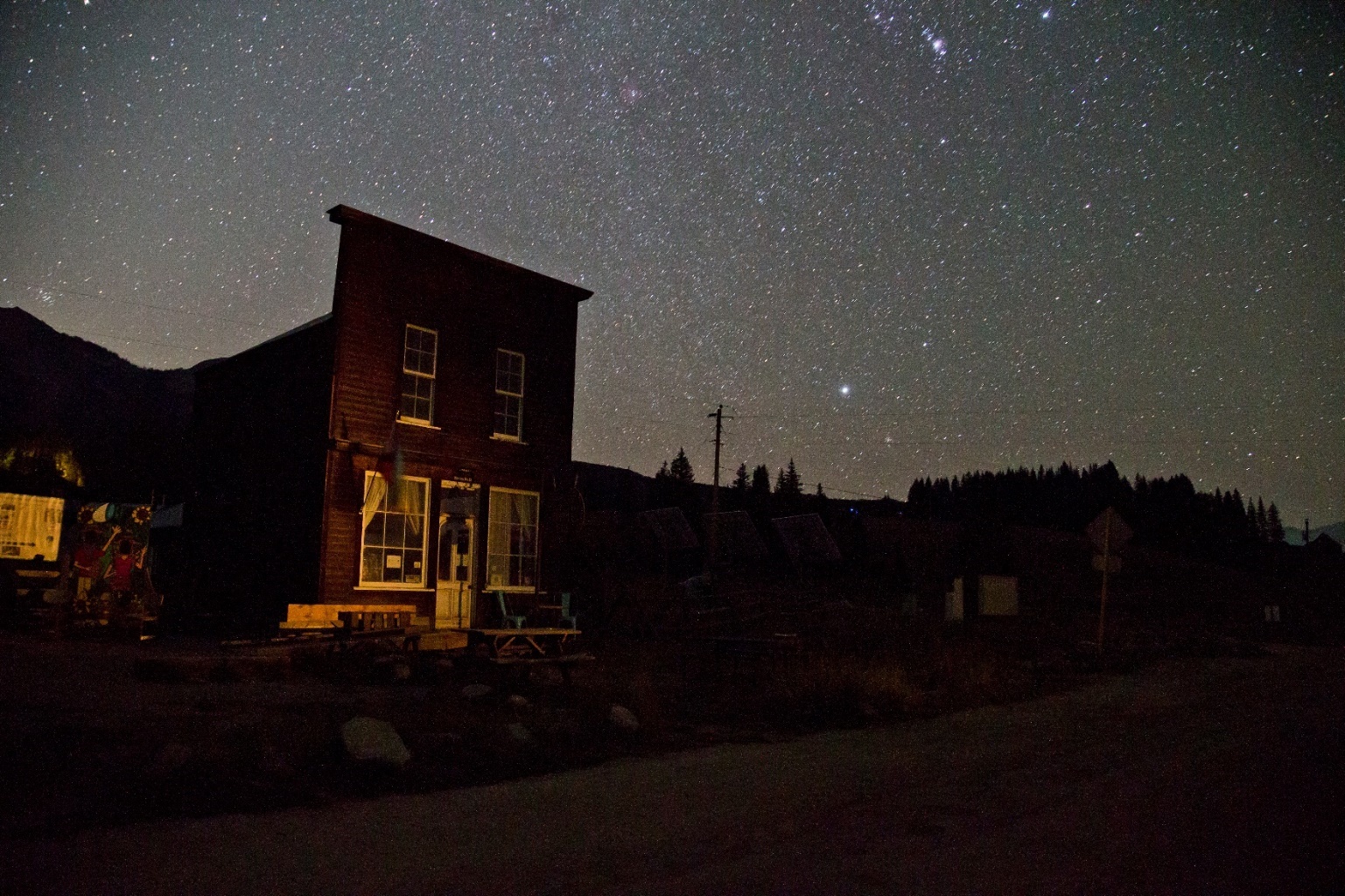 Stars fill the nighttime sky over buildings in Gothic, Colorado.