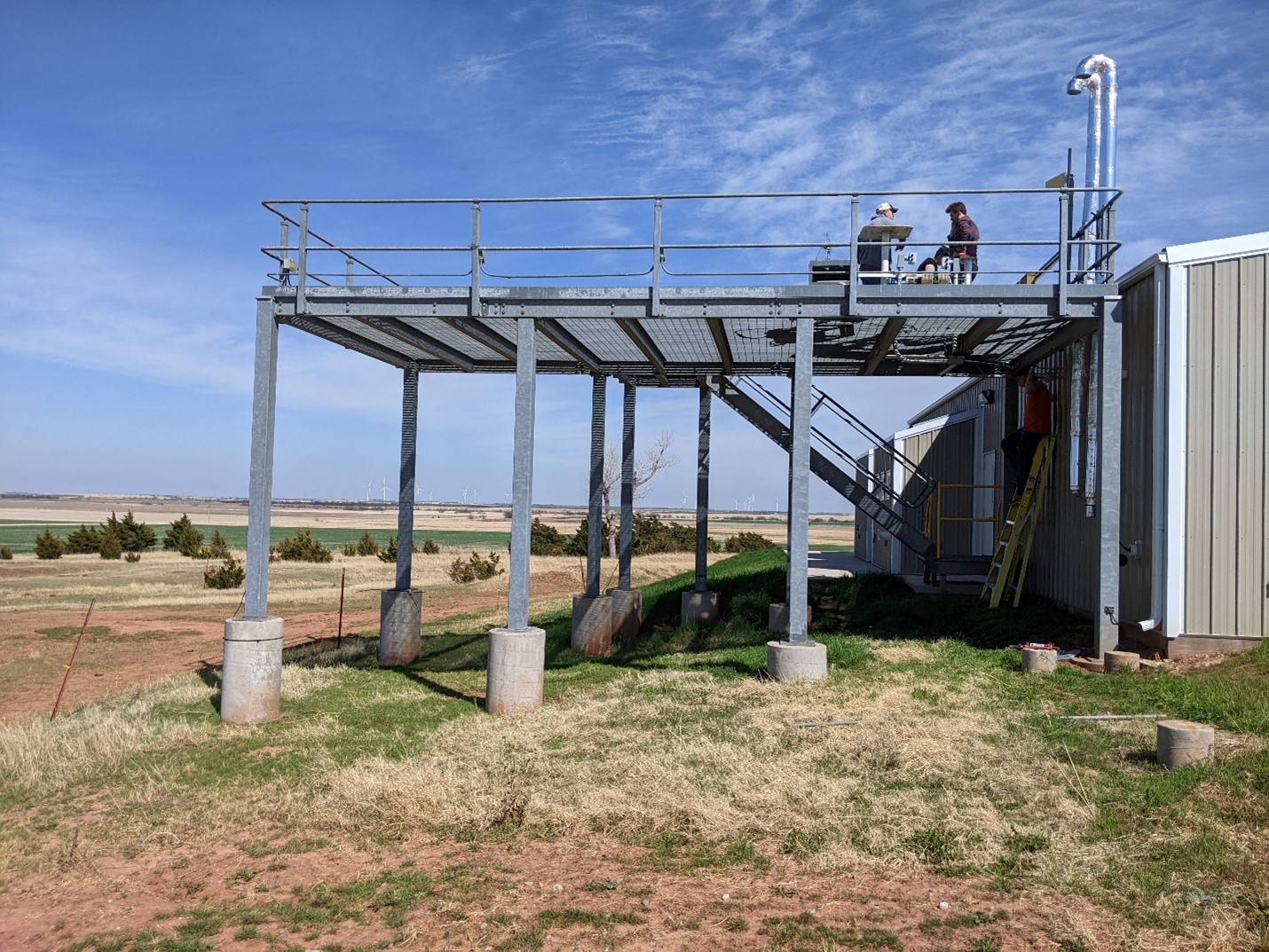 Two people talk on top of a platform at the Southern Great Plains atmospheric observatory in Oklahoma.