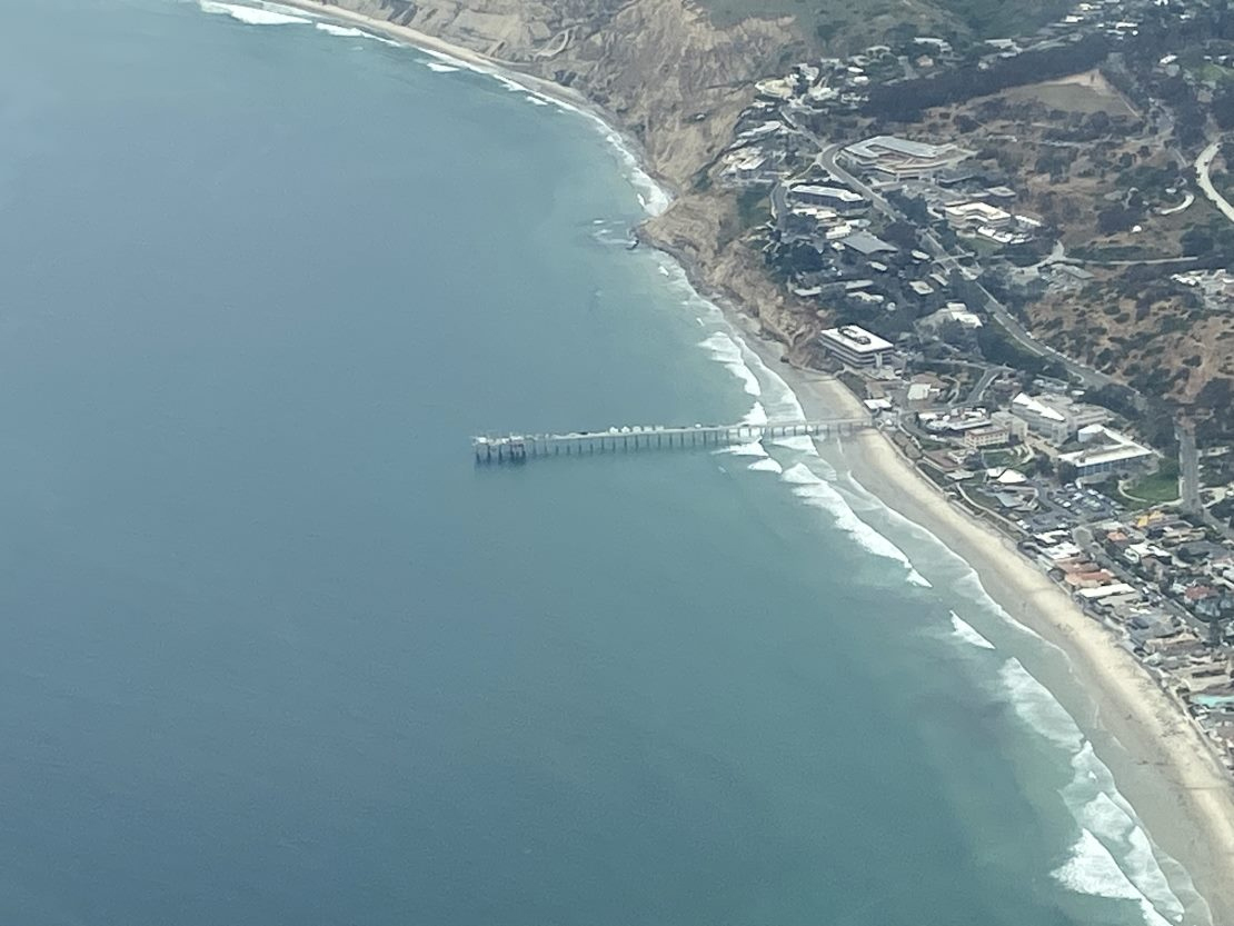 Aerial view of Ellen Browning Scripps Memorial Pier jutting into the Pacific Ocean. The westernmost part of La Jolla, California, is visible along the left side of the picture.
