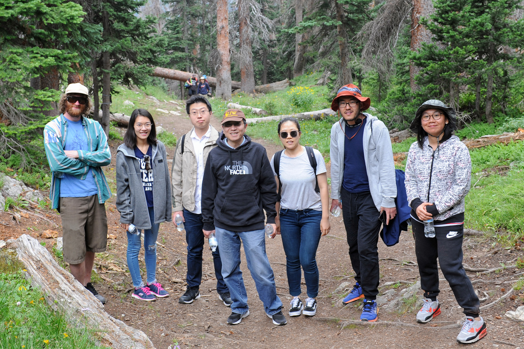 A group of seven people stop for a photo in the forest. Xiaohong Liu is in the middle of the group. Yunpeng Shan is one in from the right.