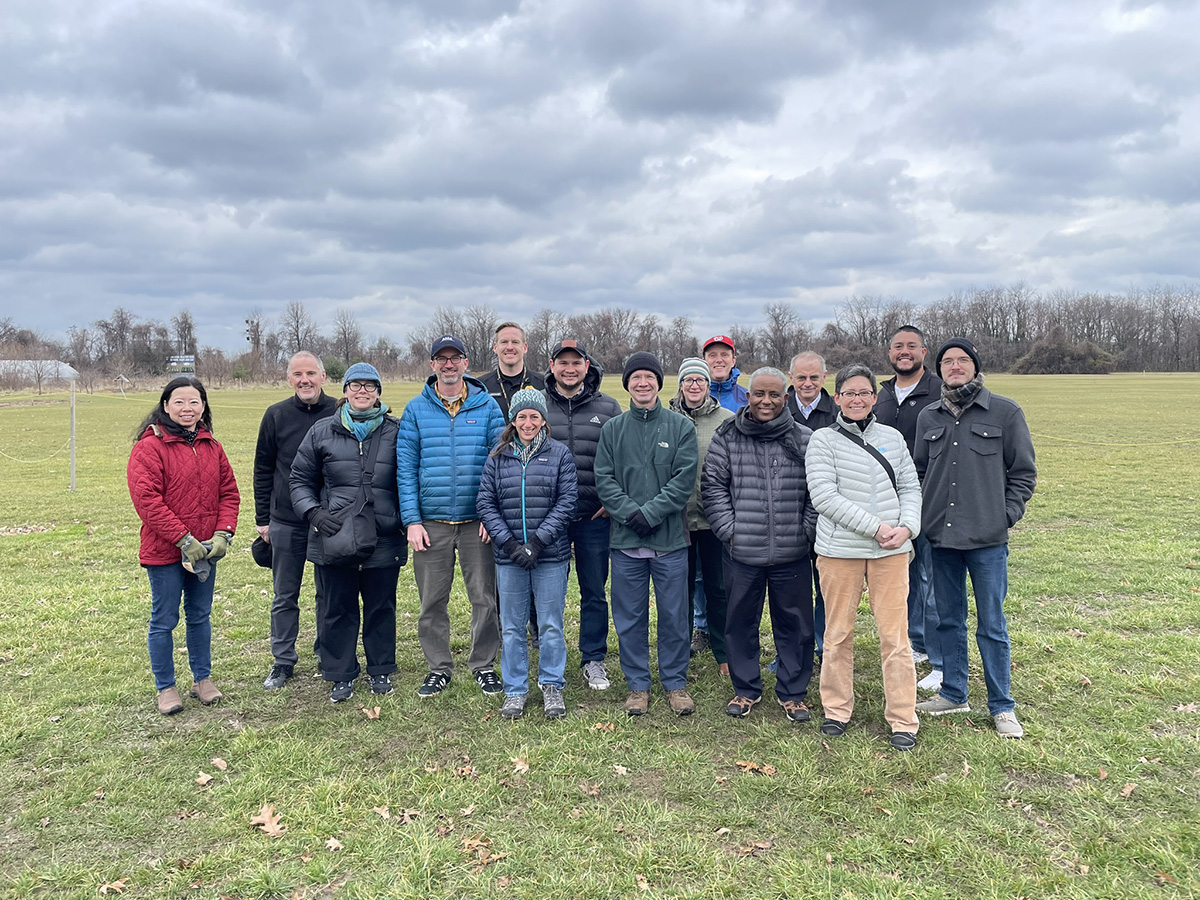 A group of CoURAGE scientists, DOE funders, and other officials stand on a field at the former Lake Clifton High School in Baltimore, Maryland.