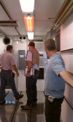 Left to right: Pat Maloy, Stephen Springston, and Mike Ritsche inspect the AMF2 AOS container. They checked for proper locations of unistrut on the ceiling, walls and floor for connecting racks and other equipment, as well as functioning of HVAC units and infrared heaters (above Mike's head). Red lights are required for nighttime ship operations, and the hatch in ceiling will accommodate the aerosol stack. ARM file photo. 